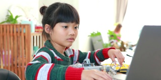小亚洲女孩在房子里的科学课上建造机器人汽车。