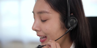 近smiley亚洲商业女接待员戴耳机视频会议电话在电脑上通过网络摄像头在网上聊天，客户支持服务的概念。