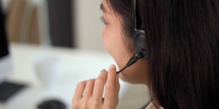 近smiley亚洲商业女接待员戴耳机视频会议电话在电脑上通过网络摄像头在网上聊天，客户支持服务的概念。
