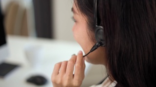 近smiley亚洲商业女接待员戴耳机视频会议电话在电脑上通过网络摄像头在网上聊天，客户支持服务的概念。视频素材模板下载