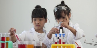 亚洲儿童穿着实验服，在家庭学校实验室里用显微镜做科学实验