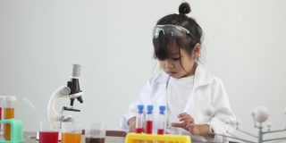 亚洲儿童穿着实验服，在家庭学校实验室里用显微镜做科学实验