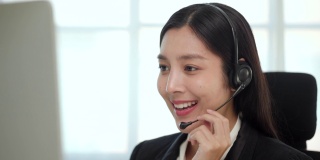 以在线教师的理念为客户提供呼叫中心服务。快乐的亚洲商业女接待员戴着耳机视频会议电话在电脑上通过网络摄像头在网上聊天