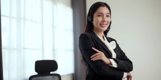 美丽的职业女性戴着耳机，自信地站在办公室视频会议。以在线教师的理念为客户提供呼叫中心服务。