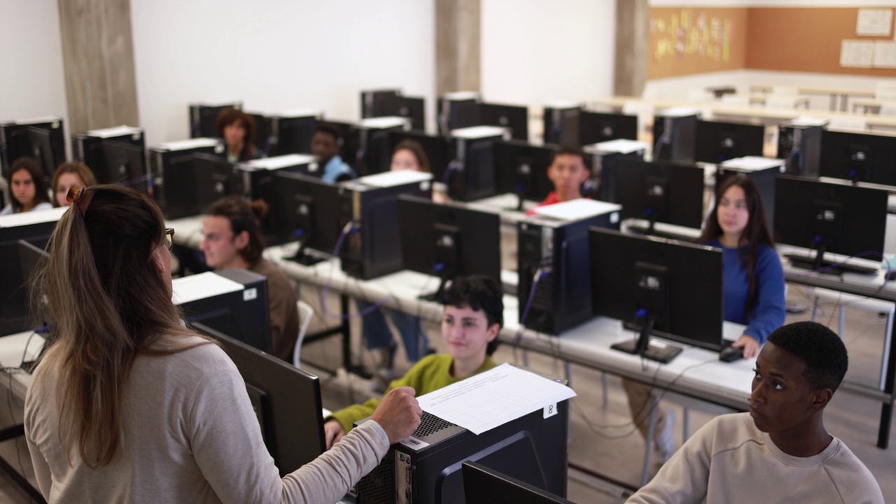 在大学计算机室内与多种族学生合作的成熟教师