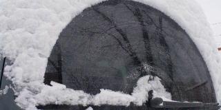 后雨刷清除汽车后窗上的雪。汽车玻璃刷清洁白雪