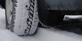 汽车陷在雪里了。下雪后，雪从旋转的车轮上飞起。