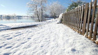 白雪覆盖的地面上有一道木栅栏，还有一只鸭子在湖里游泳视频素材模板下载