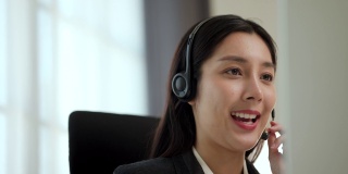 以在线教师的理念为客户提供呼叫中心服务。快乐的亚洲商业女接待员戴着耳机视频会议电话在电脑上通过网络摄像头在网上聊天