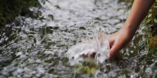 儿童用手触摸大自然中的水。河水在森林里流淌。自然与生命理念。新鲜的溪水