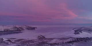 冻结的湖的北方景观无人机飞行下来与美丽的倒影在冰在日落。令人惊叹的冬季贝加尔湖，红色的日出。看一架无人机在北部冰湖上飞行。自然反射日落