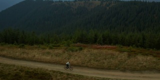 空中山地骑自行车的人有乐趣丘陵道路对岩石绿色的派克