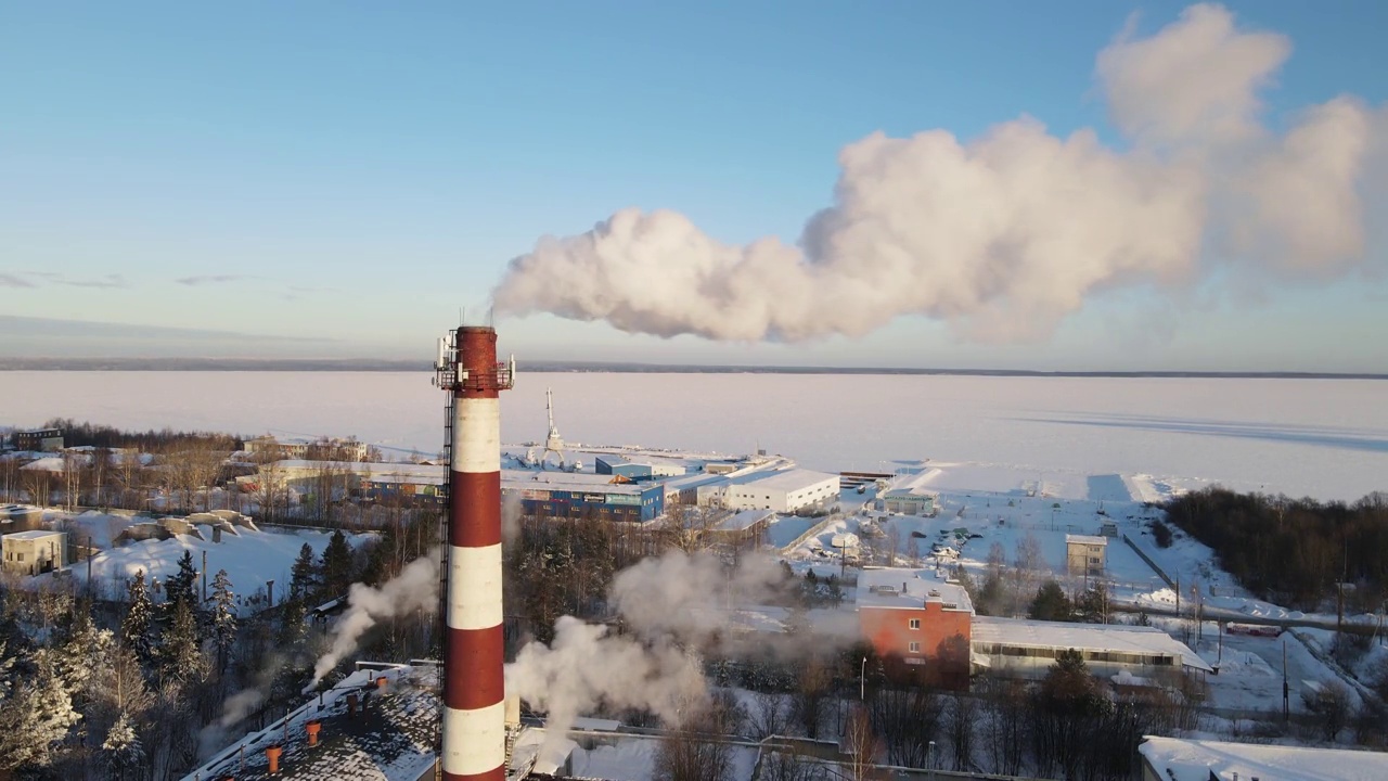 工业区有一个大的红白相间的管，浓浓的白烟从工厂的管中倾泻而出，与太阳形成对比。环境污染:有烟的烟斗。鸟瞰图