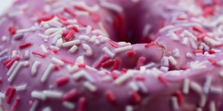 甜美可口的甜甜圈的特写，上面覆盖着粉色的糖霜。美味的茶点。甜甜圈旋转。面包店里烤的快餐。选择性聚焦，浅景深