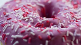 甜美可口的甜甜圈的特写，上面覆盖着粉色的糖霜。美味的茶点。甜甜圈旋转。面包店里烤的快餐。选择性聚焦，浅景深视频素材模板下载