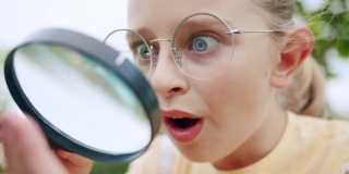 一个十几岁的女孩通过放大镜观察昆虫的微观世界。