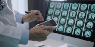 医生用数码平板电脑分析病人的脑部扫描图