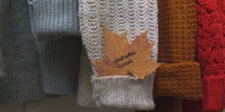 秋天的概念。女手把枫叶和文秋心情放在舒适暖和的毛衣上。针织羊毛衫和马海毛毛衣。Hygge风格