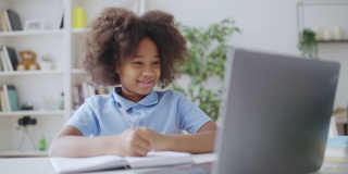 可爱的非洲裔美国女学生在家里用笔记本电脑上在线视频课