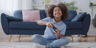 微笑的小女孩在家里玩电子游戏，快乐无忧无虑的童年