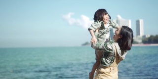 4K快乐的母亲在沙滩上举起可爱的小女孩