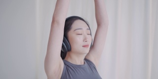 年轻的亚洲女性用无线耳机练习瑜伽冥想