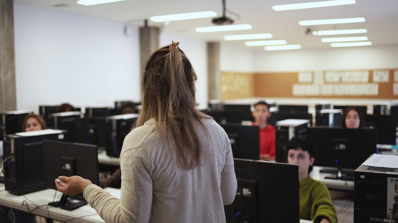 女教师在学校电脑室与学生一起工作