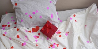 带着蝴蝶结和红心的礼盒在床上飞舞。情人节礼物