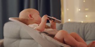 有趣的孩子看电视节目系列动画片，拿着电视数字媒体播放器的遥控器，9个月大的婴儿的脸特写。