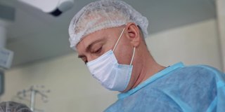 由专家进行的外科手术。穿着医疗制服的医生在现代手术室进行手术的团队合作。