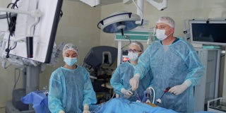 主刀外科医生在手术中使用医疗设备，看着显示器显示病人的内部器官。两名医生协助主刀外科医生。技术在外科手术中的应用。