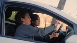 驾校的女教师正在教年轻女子如何开车。视频素材模板下载
