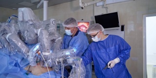 男性外科医生站在机器人设备旁。技术机器人在手术室为病人进行手术。