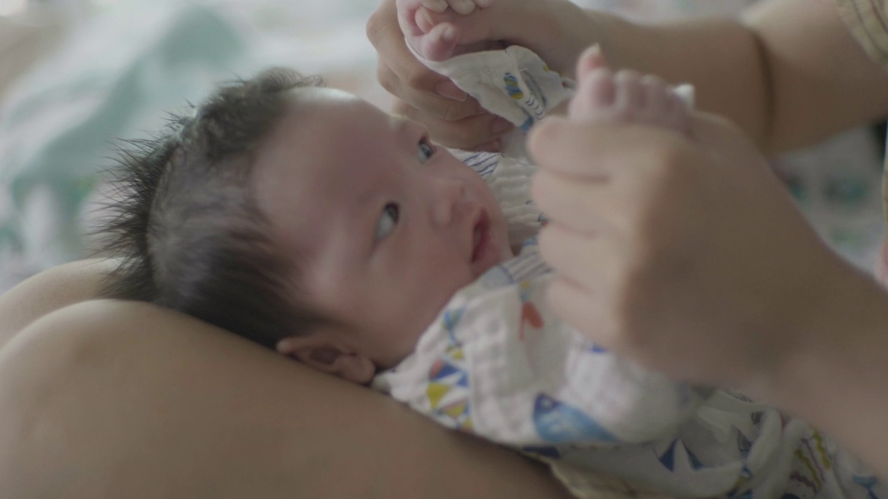 近距离亚洲妈妈手握新生男婴玩他在家里。