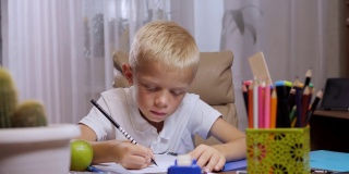 一个小男生正坐在办公室的软椅上写笔记本。