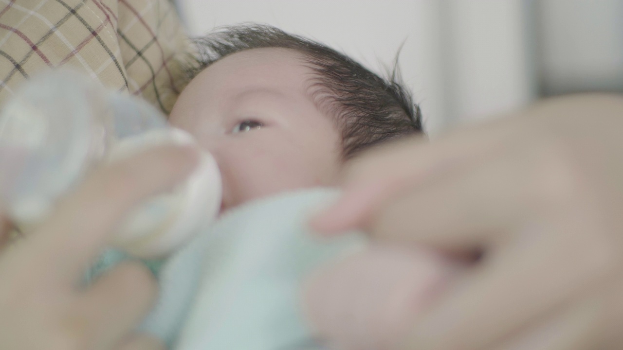 近距离亚洲妈妈手握新生男婴玩他在家里。