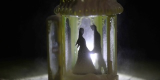 一个男人和一个女人的轮廓在夜晚下雪的凉亭