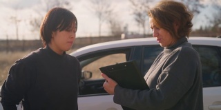 女驾驶教练在车外与女驾驶学校学员交谈