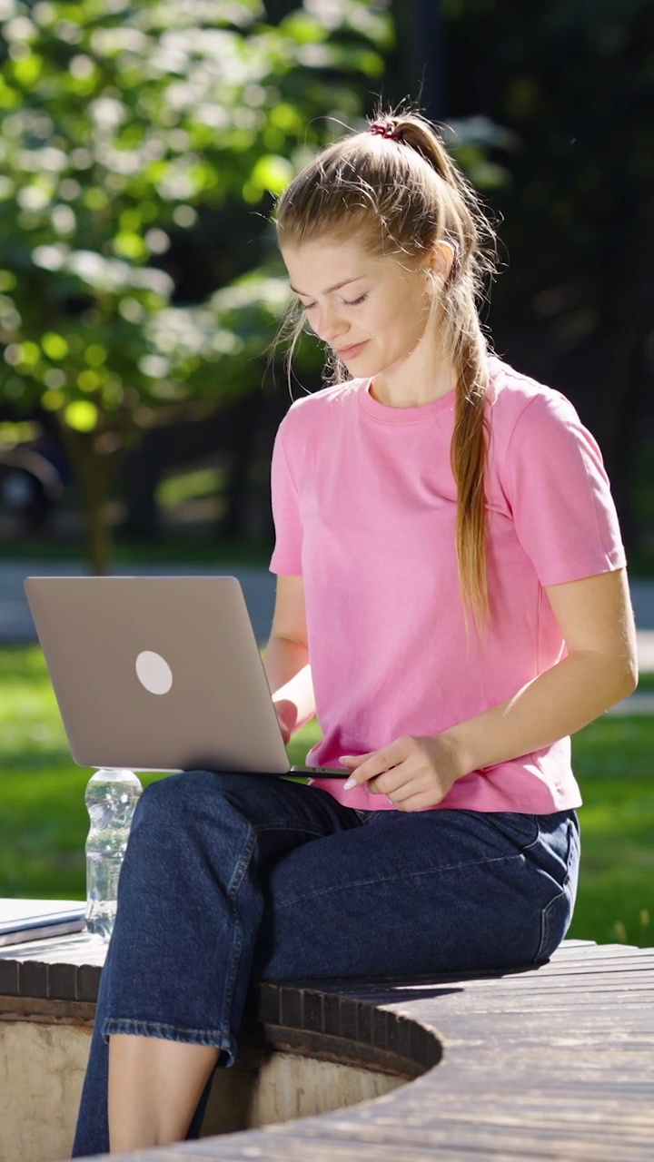 垂直屏幕:在公园里用笔记本电脑工作的女性