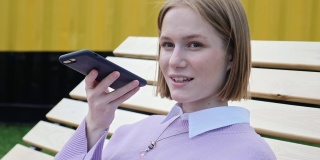 年轻的金发女子在智能手机上录语音信息