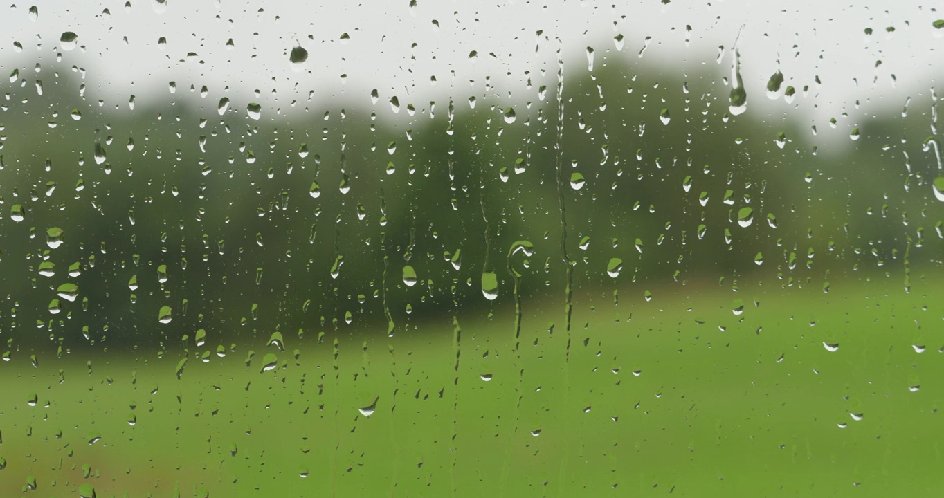 小雨打在玻璃上。夏天的雨雨滴沿着窗户落下。外面雨窗口。淋浴坏天气。平静放松的冥想宁静的背景。雨天，秋天，忧郁，悲伤，孤独