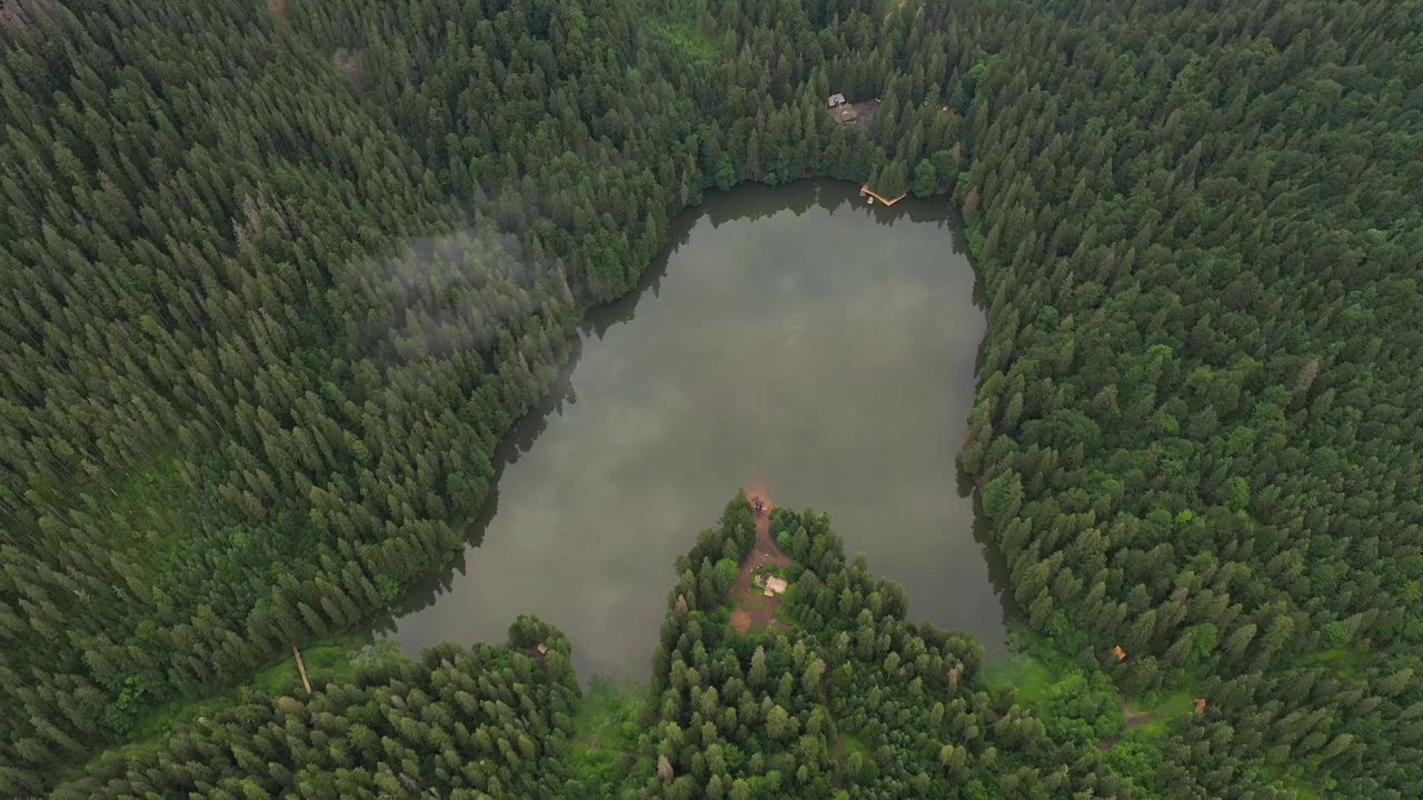 一架无人机飞过一个被森林包围的小湖。