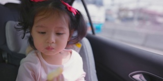 蹒跚学步的小女孩与家人旅行时坐在汽车安全座椅。