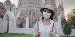 带着口罩的亚洲女性游客正在泰国曼谷的阿伦寺旅行。