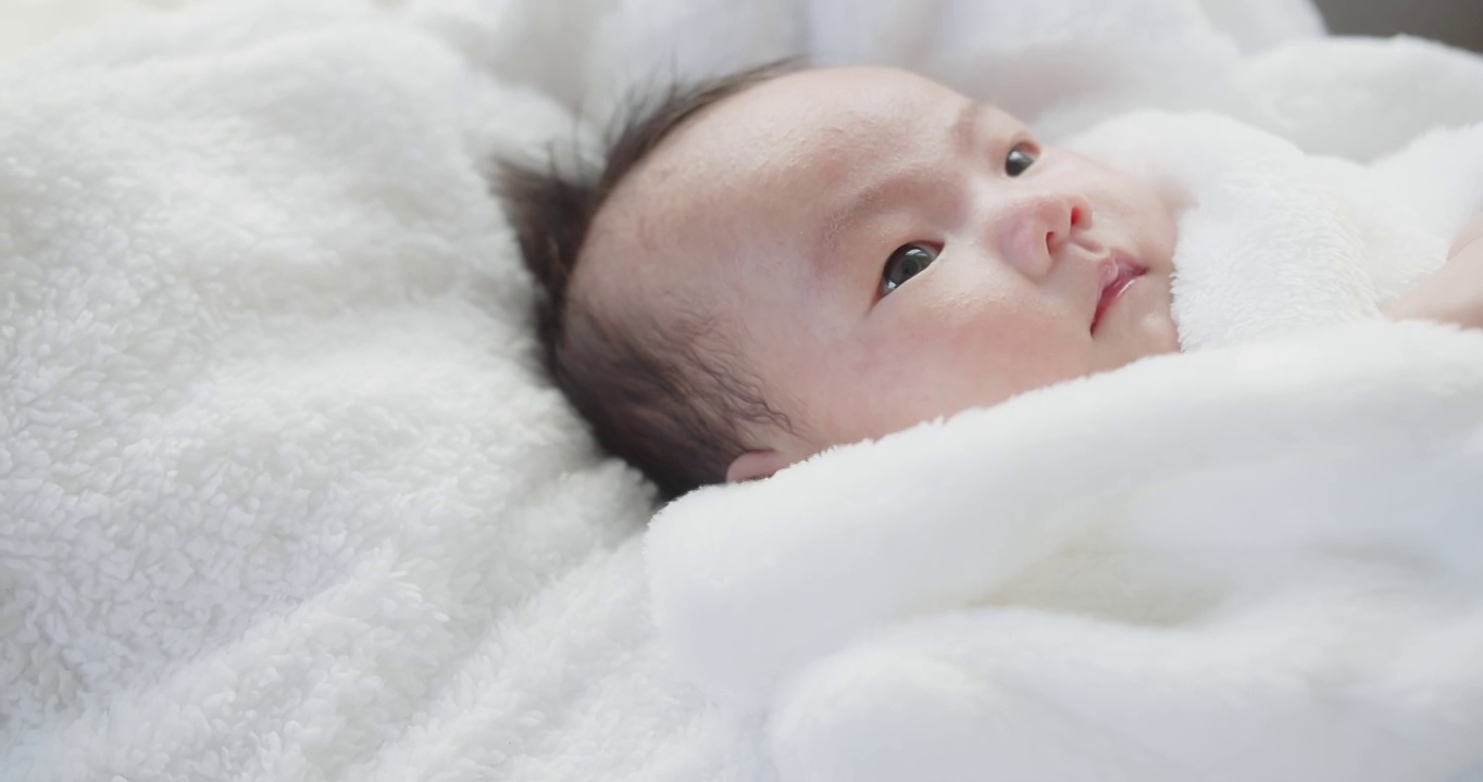 肖像特写漂亮的亚洲新生婴儿婴儿女孩在白色浴衣躺在床上的一个篮子在家里的眼睛睁开，孩子，父母，童年，生活，母性，爱的概念