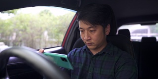 亚洲年轻人在停车时在车里用手机。