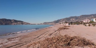 一架无人机在一场强风暴后飞越了布满树木残骸的肮脏海滩。大雨过后，阿兰亚海滨的沙滩上堆满了垃圾。全球污染环境