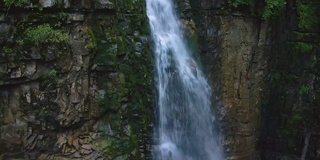 在夏天的热带雨林中，美丽的山河瀑布和白色的泡沫水从岩石悬崖上落下