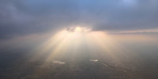 高空鸟瞰图，远处的城市被傍晚暴雨前形成的蓬松的积云所覆盖。飞机角度多云的景观