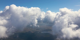 从飞机窗口俯瞰，高空的地面上覆盖着白色蓬松的积云